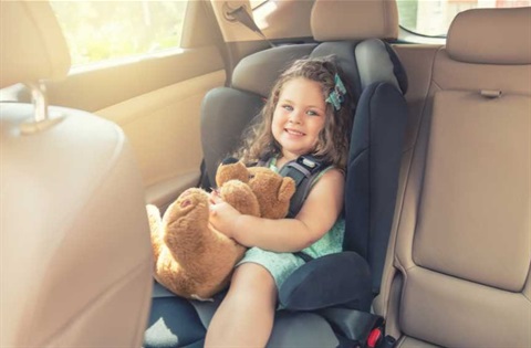 Young girl in car seat holding teddy bear